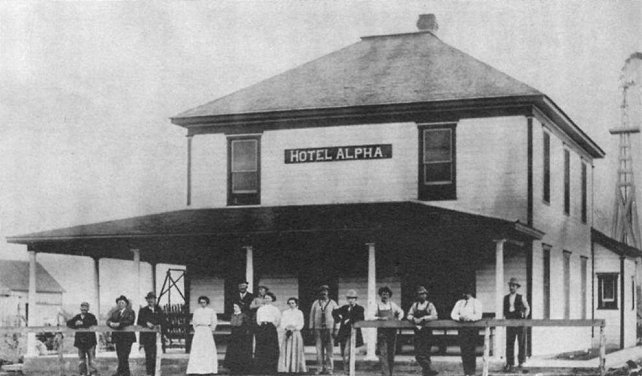 The ALPHA HOTEL at Wilmore, Comanche County, Kansas,  one of the county's prominent hostelries, was well patronized by the ranchers and townspeople and was also a social center. Shown are the Albert Heflins, hotel managers;   Bruce Snare,  Francis Larimer,  Mr. McGraflin, lumberman;  Mrs. Thos. Wilmore  and son  Ray;  Tom De Jarnett  and  Sallie Davis. A 1908 photo published in the Diamond Jubilee Historical Souvenir Program. Coldwater, KS: Western Star, 1959.