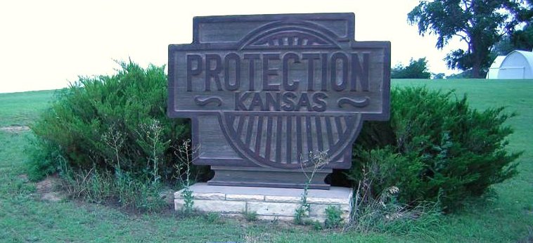 Sign designed by Stan Herd at the south side of Protection, Comanche County, Kansas.  Photo by Orlin Loucks, 19 June 2005.