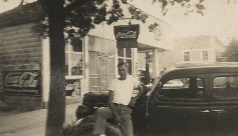 Wendel Ferrin with his 1935 Ford in front of Ernest Wood's cafe, Wilmore, Comanche County, Ks, about 1944.