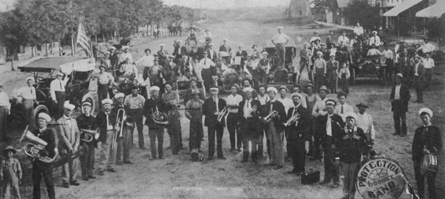 A 1910 picture of Protection Boosters and Band lookin north on Main Street, Protection, Comanche County, Kansas.  Photo from the Diamond Jubilee Historical Souvenir Program. Coldwater, KS: Western Star, 1959.