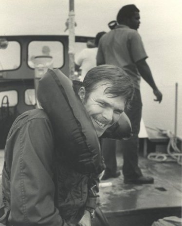 Photographer's Mate 3rd Class Dick Mckie, Air Crew, on a recovery boat in the Salton Sea just after his first parachute jump. PH2 Frank DeVance is in the background.  Photo by PHAN Jerry Ferrin, circa 1975.