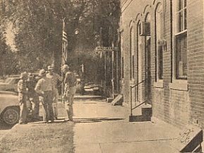 Wilmore had many visitors following the bank robbery Wednesday night of last week.  This photo, taken early Thursday morning of the east side of the bank and post office, shows a group of natives exchanging comments on the robbery.